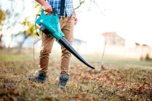 Gardener clearing up leaves using an electric leaf blower